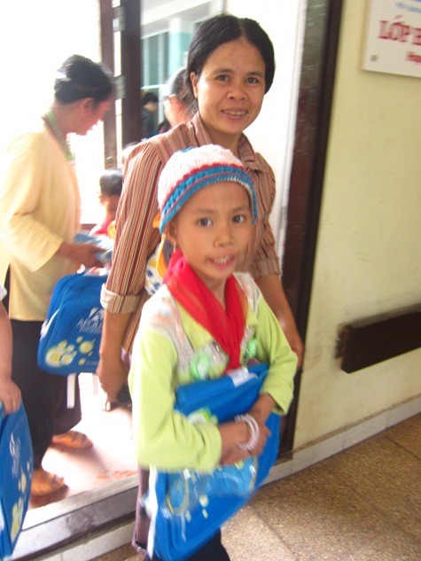 Mẹ cùng bé Thảo vui mừng được quàng khăn đỏ, cầm cặp sách mới trong buổi đầu tiên đến lớp học Hy vọng