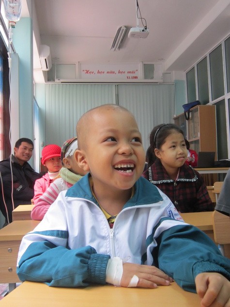 Sơn cười thật nhiều để khỏe mạnh trong giờ học cười của thầy Huy vui tính ở lớp học Hy vọng. Trên tay em chằng chịt mũi truyền