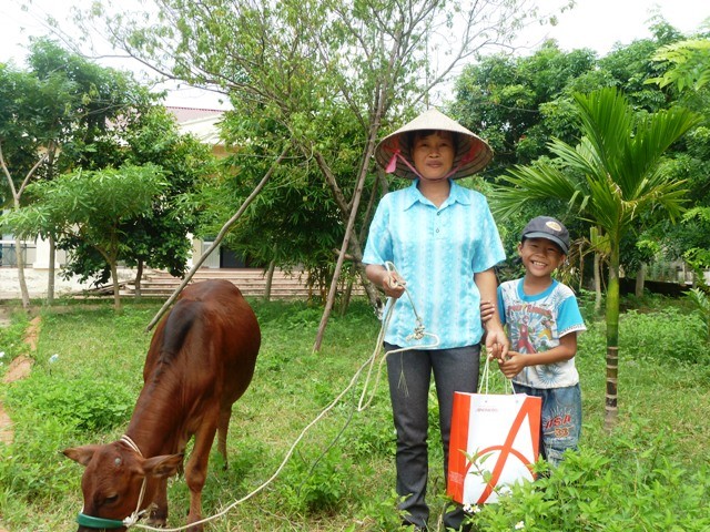 Em Ôn Văn Tĩnh (phải) cùng mẹ vui mừng vì được các nhà hảo tâm hỗ trợ mua được con bò để gây vốn.