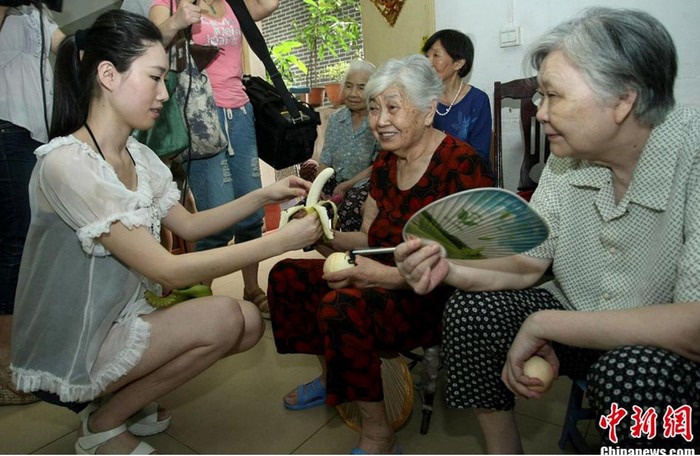 Hoa hậu Nghiêm Manh bóc chuối cho các cụ già trong vêện dưỡng lão.