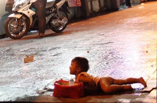 Đứa bé khóc thét lên để lấy lòng thương của những người qua đường, thực ra đây chỉ là màn diễn dưới sự giật dây của bọn chăn dắt trẻ em. Ảnh. Tuổi Trẻ.