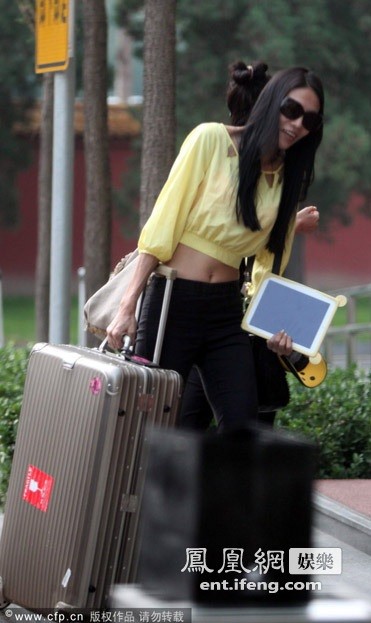 Một nữ diễn viên xách hành lý và tư trang cho Thành Long.