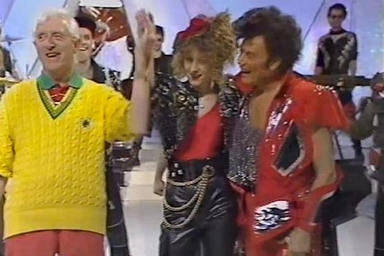 Hai kẻ ấu dâm là Jimmy Savile (áo vàng) và ca sĩ Gary Glitter (ngoài cùng bên phải) cùng vũ công Karin Ward (giữa) trong chương trình Jim'll Fix It của Savile.