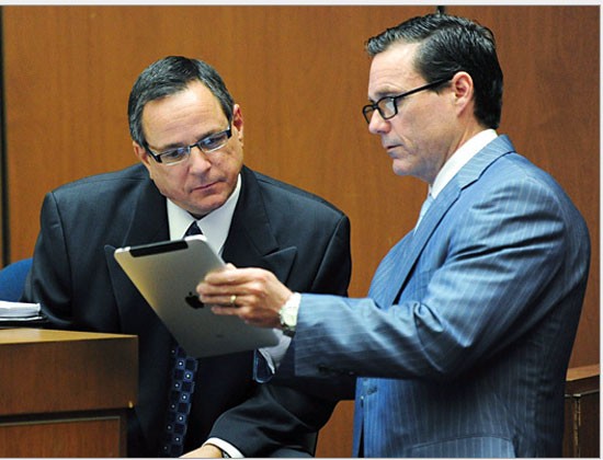 Cảnh sát Los Angeles Detective Scott Smith (trái), đọc thông tin từ phòng luật sư Ed Chernoff trong vụ điều tra bác sĩ Conrad Murray và cái chết của ngôi sao nhạc pop Michael Jackson tại Los Angeles trên iPad.