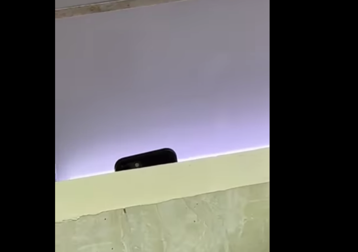 Chiếc điện thoại đang thực hiện quay lén được nam sinh quay lại khi vào nhà vệ sinh (ảnh cắt từ clip)