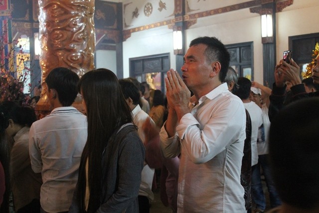 Một người đàn ông đang chấp tay cầu nguyện tại chánh điện