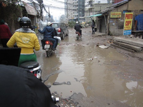 Nhiều hố ga và vũng nước lớn ngập lụt trên đường gây khó khăn cho người đi lại. (Ảnh: Bùi Nhung)