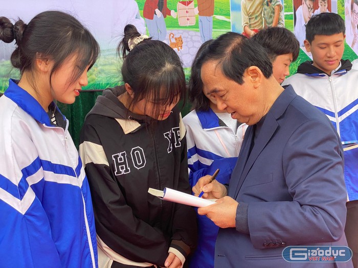Giáo sư Nguyễn Lân Dũng ký tặng sách cho các em học sinh (Ảnh: Phạm Minh)