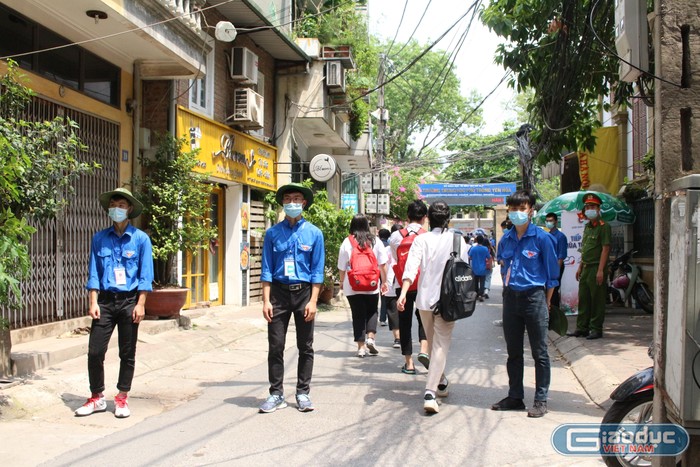 Học sinh lớp 11 tham gia tình nguyện tại điểm thi Trường Trung học phổ thông Yên Hòa. (Ảnh: Phạm Minh)