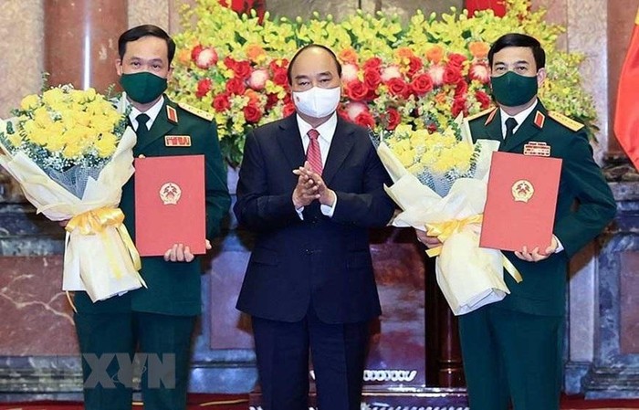 Chủ tịch nước Nguyễn Xuân Phúc trao quyết định thăng quân hàm, tặng hoa chúc mừng Bộ trưởng Quốc phòng Phan Văn Giang (phải) và Thứ trưởng Vũ Hải Sản.