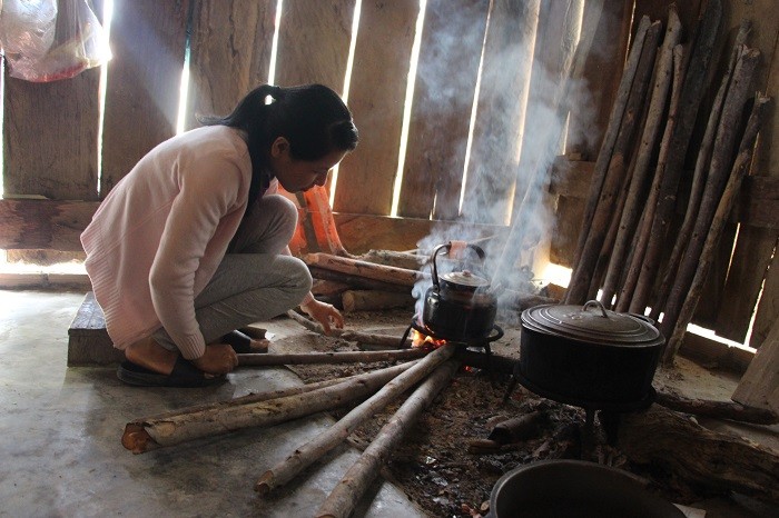 Cô Trần Thị Duyên thổi lửa chuẩn bị bữa cơm tối tại khu tạm trú. (Ảnh: tác giả cung cấp).