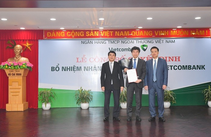 Chủ tịch Hội đồng quản trị Vietcombank Nghiêm Xuân Thành (bên trái) và Tổng Giám đốc Vietcombank Phạm Quang Dũng (bên phải) trao Quyết định và tặng hoa chúc mừng Ông Eiji Sasaki được bổ nhiệm là Thành viên Hội đồng quản trị kiêm Phó Tổng Giám đốc Vietcombank.