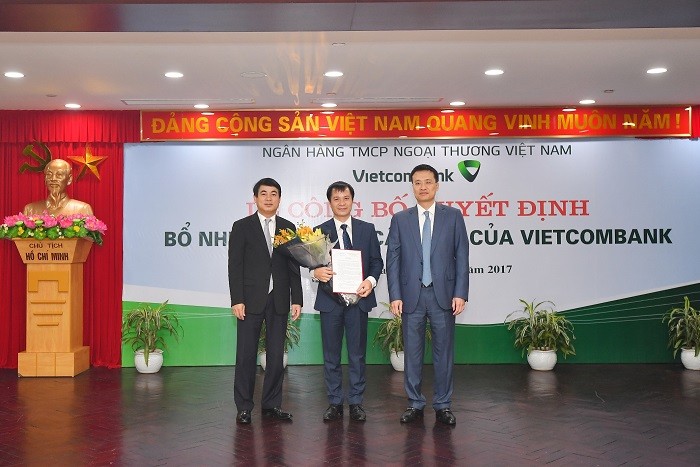 Chủ tịch Hội đồng quản trị Vietcombank Nghiêm Xuân Thành (bên trái) và Tổng Giám đốc Vietcombank Phạm Quang Dũng (bên phải) trao Quyết định và tặng hoa chúc mừng Ông Lê Hoàng Tùng – tân Kế toán trưởng Vietcombank.