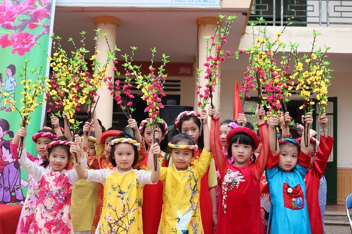 Một số em học sinh trong trang phục áo dài truyền thống, mang hoa để cổ vũ U23 Việt Nam.