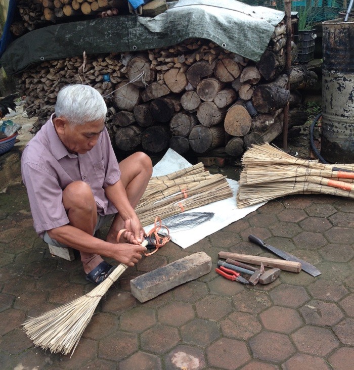 Ông ngoại của em Phạm Ngọc Thư đang đan chổi để bán (Ảnh: tác giả cung cấp).