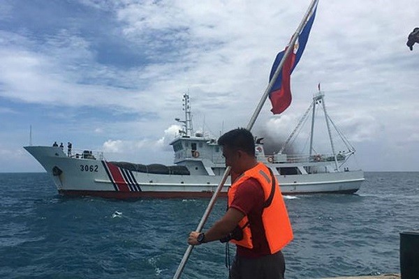 Một công dân Philippines cắm cờ Philippines trên khu vực thuộc bãi cạn Scarborough trước tàu Hải cảnh của Trung Quốc (Nguồn ảnh: TTXVN).