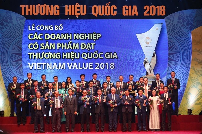 Phó Thủ tướng Trịnh Đình Dũng và Bộ trưởng Bộ Công Thương Trần Tuấn Anh chụp ảnh lưu niệm cùng đại diện các doanh nghiệp có sản phẩm được công nhận Thương hiệu Quốc gia năm 2018.