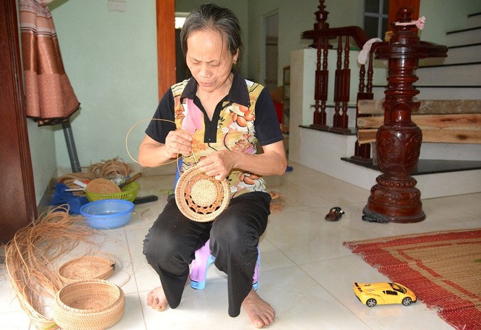 Hàng tháng cô giáo Trần Thị Thoa vẫn đi dạy học miễn phí và nhận thêm làm đồ mây tre đan xuất khẩu tại nhà, trông cháu nội ngoại giúp các con. Ảnh: Công Tiến