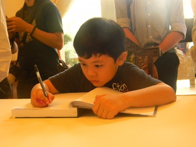 Cậu bé Bùi Quang Kiên chăm chú gò từng nét chữ trên sổ tang Đại tướng