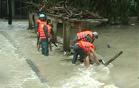 Lực lượng cứu hộ cùng với người dân đang ra sức tháo gỡ chướng ngại vật vướn vào đập thủy lợi Bàu Le