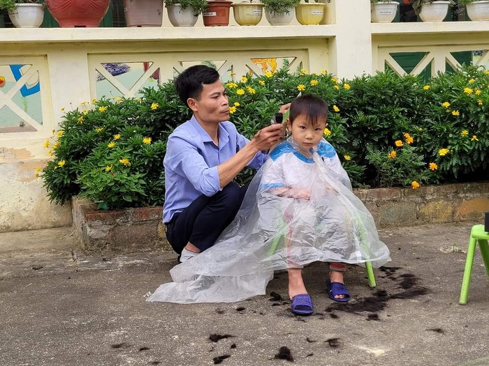 Thầy giáo mầm non Lê Văn Thắng đang cắt tóc cho học trò. Ảnh nhân vật cung cấp.