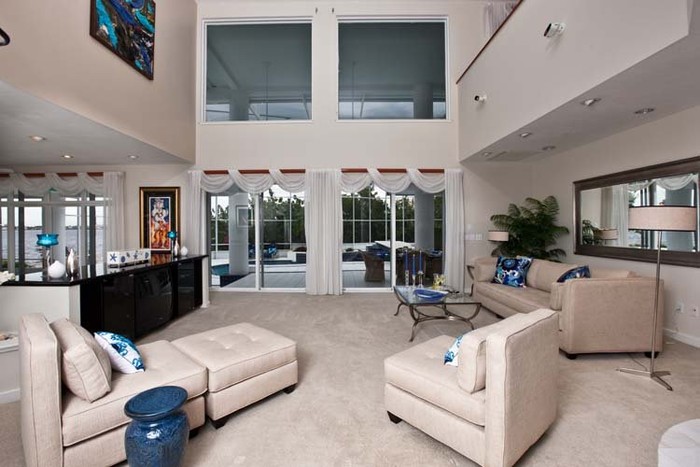Phòng khách có trần nhà cao với những bộ sofa cùng tông màu với tường, không gian khoáng đãng
