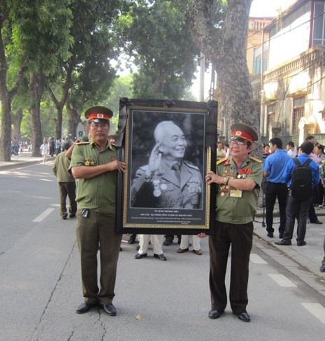 Hai cựu chiến binh huân chương đầy ngực áo nâng cao ảnh Đại tướng Võ Nguyên Giáp.
