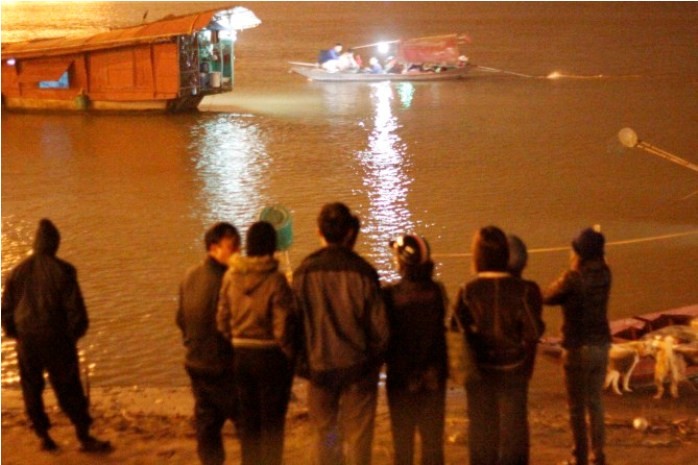 Đông đảo người nhà nạn nhân đứng trên bờ sông mong ngón tin tức từ đội thợ lặn vào tối 24/10.