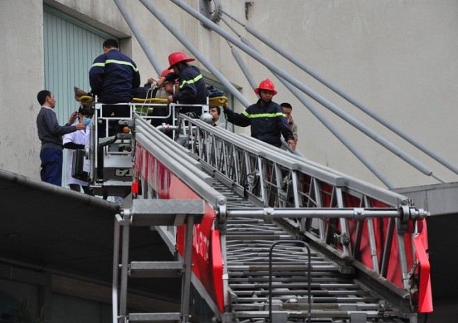 Lực lượng chức năng dùng xe thang đưa nạn nhân xuống đất.