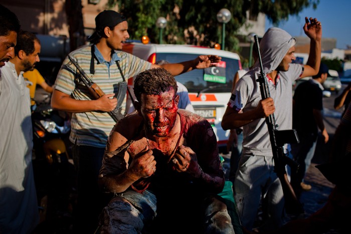 19. Một tay súng thân đại tá Gaddafi bị thương nặng đang được những phiến quân bảo vệ trước sự giận dữ và căm ghét của nhiều người.