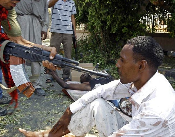 6. Lính nổi dậy đang chĩa súng vào một người đàn ông bị bắt vì tình nghi thuộc phe ủng hộ đại tá Gaddafi.