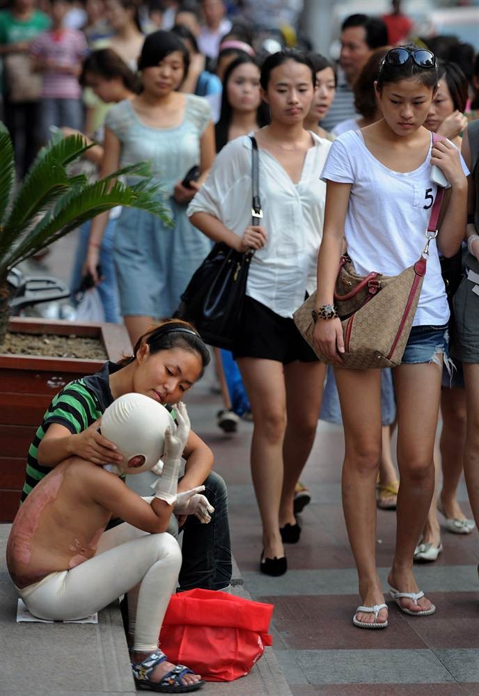 Hai mẹ con người Trung Quốc đang xin bố thí trên một con phố ở Hợp Phì. Con trai của người phụ nữ bị bỏng nặng trong một trận hoả hoạn cách đây 3 tháng (ảnh chụp ngày 4/9/2011).