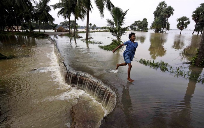 Một cô bé chạy qua con đường bị nước lụt gây ngập gần Bhubaneshwar, Ấn Độ ngày 16/9/2011. Ít nhất 26 người đã thiệt mạng vì lũ lụt tại 19 quận, huyện tại bang Orissa tính từ giữa tháng 9 vừa qua.