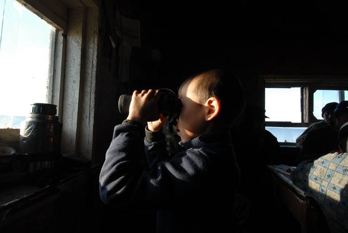Con trai của một thợ săn đang sử dụng ống nhòm để quan sát cá voi xuất hiện ngoài biển.