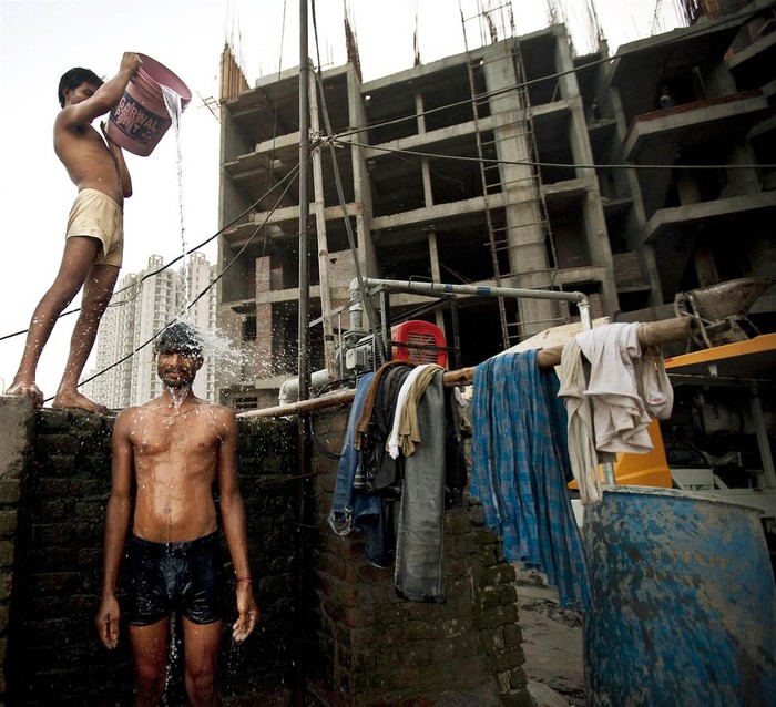 Một công nhân lao động Ấn Độ được đồng nghiệp dội nước trong lúc tắm cuối ngày tại một công trình xây dựng đang giang dở ở New Delhi (ảnh chụp ngày 26/9/2011).