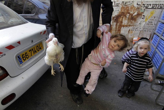 Cảnh một người đàn ông Do Thái một tay xách con gái, một tay xách gà ở Jerusalem.