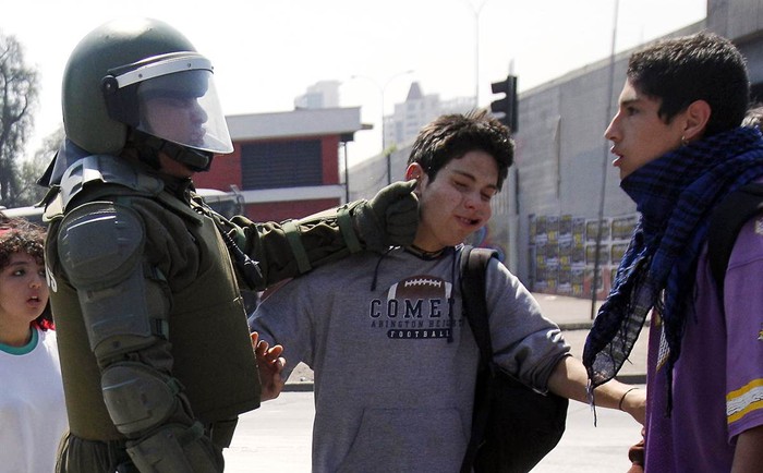 Cảnh một viên sỹ quan cảnh sát chống bạo động giáng một cú đấm vào mặt một thiếu niên tham gia biểu tình ở Santiago, Chile.