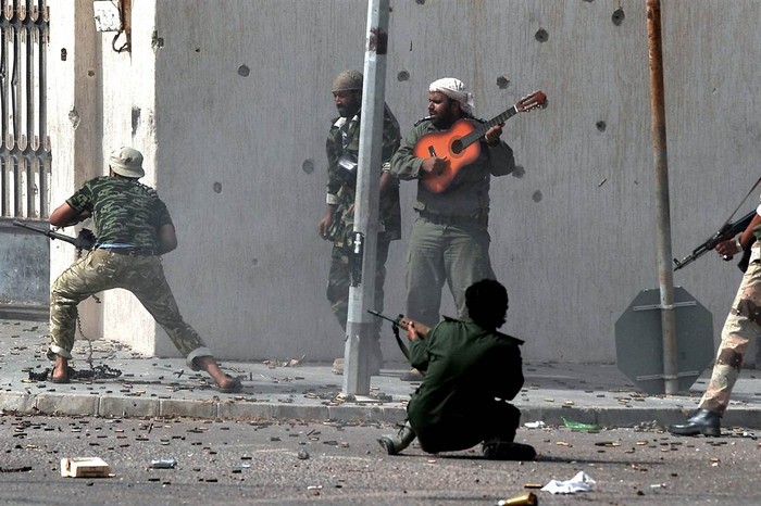 Quân nổi dậy bình thản chơi đàn giữa tiếng súng đạn chát chúa ở Sirte, Libya.