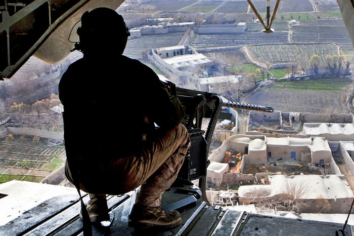 Một binh sỹ Mỹ đang ngồi cạnh khẩu súng máy lắp sau đuôi một chiếc máy bay đang tuần tra trên bầu trời tỉnh Helmand, Afghanistan (ngày 5/1)