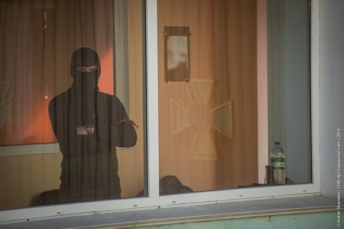 Một người đàn ông trùm khăn che mặt đang đứng quan sát bên ngoài của một toàn nhà