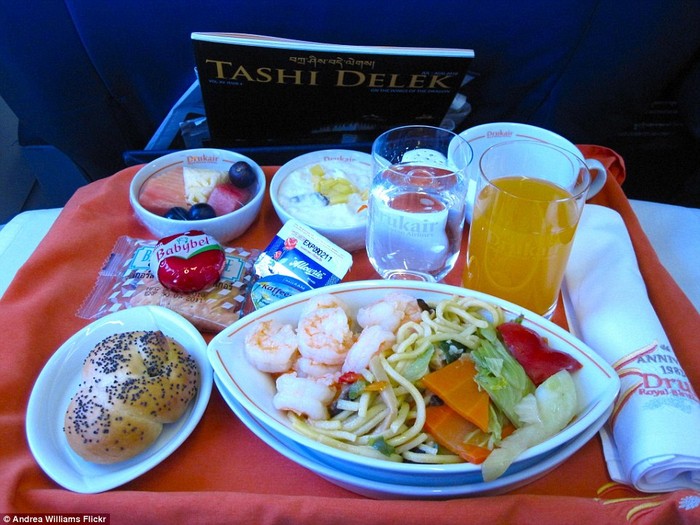 Bữa ăn của hãng hàng không Drukair, Bhutan với nhiều món: mì xào với các loại rau và tôm, nước cam hoặc nước tinh khiết, salad hoa quả, sữa chua kem.
