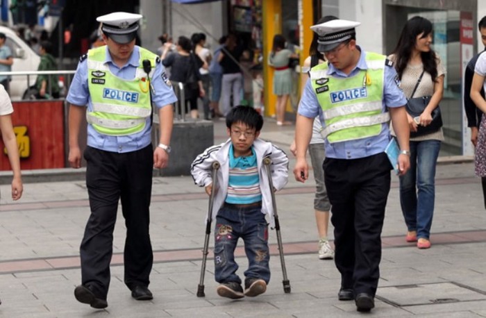 Bạn Nguyễn Kinh Thiên 18 tuổi nhưng chỉ cao có 1m1, cùng với bị dị tật bẩm sinh nên rất khó đi lại. Hai chú cảnh sát đang hộ tống bạn ấy để đến tham dự kì thi đấy. (Ảnh: Kenh14)