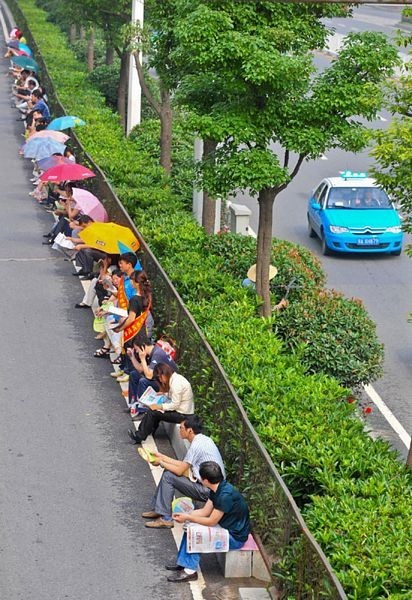 Các phụ huynh ngồi đợi thành hàng dài bên ngoài một hội đồng thi ở Vũ Hán, tỉnh Hồ Bắc. (Ảnh: Dantri)