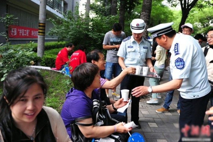 Tại một hội đồng thi ở quận Xicheng, thành phố Bắc Kinh, phụ huynh được lực lượng cảnh sát, an ninh phân phát nước uống giải nhiệt trong lúc chờ sĩ tử. (Ảnh: Kenh14)