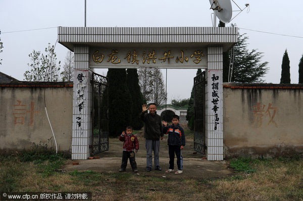 Hiệu trưởng Wang Jinlong chụp ảnh cùng hai học sinh trước cổng trường.