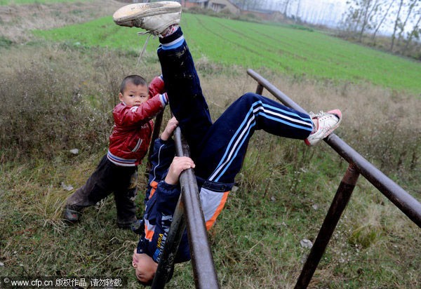 Yang Nieyuan và Li Juncheng chơi trên xà kép – thiết bị thể dục duy nhất tại trường học ở làng Shuangmiao