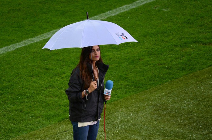 Trong khi Shakira ngồi thảnh thơi trên khán đài xem bạn trai thi đấu, Sara Carbonero, cô bạn gái phóng viên của thủ môn Casillas phải vất vả cầm ô che mưa tác nghiệp dưới sân. .