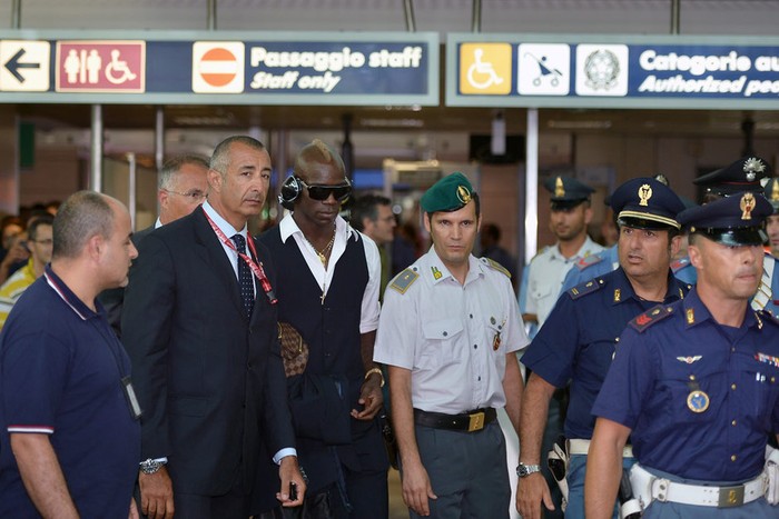 Mario Balotelli được các nhân viên an ninh bảo vệ khi rời khỏi sân bay ở Rome