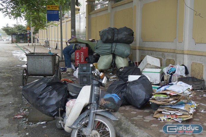Công nhân thu gom xong lại bày rác ra hè phố để lựa những phế liệu đem bán trên hè đường Mỹ Đình. Ảnh: Tùng Dương.