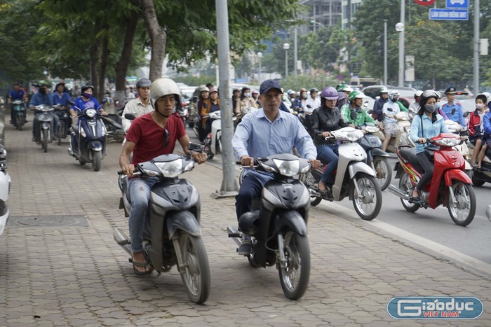 Xe máy đi tràn lên vỉa hè phố Lê Văn Lương ảnh hưởng đến người đi bộ. Ảnh: Tùng Dương.